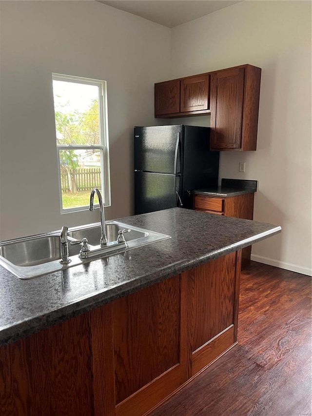 kitchen featuring dark wood-type flooring, black refrigerator, and sink