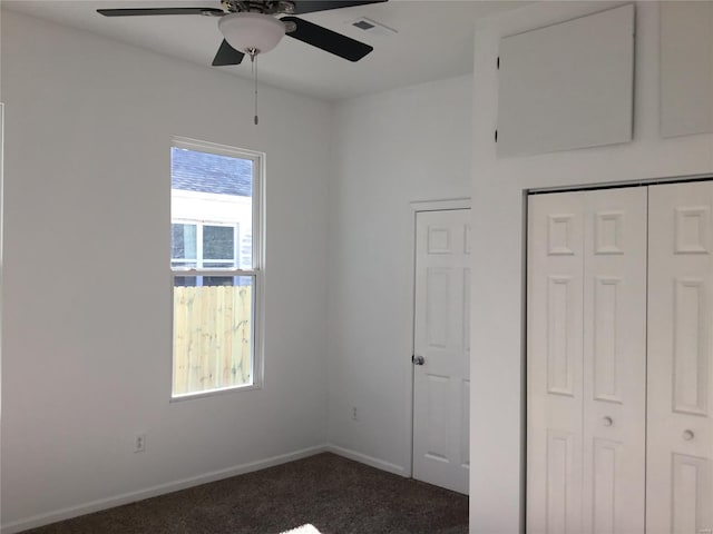 unfurnished bedroom with a closet, dark carpet, and ceiling fan