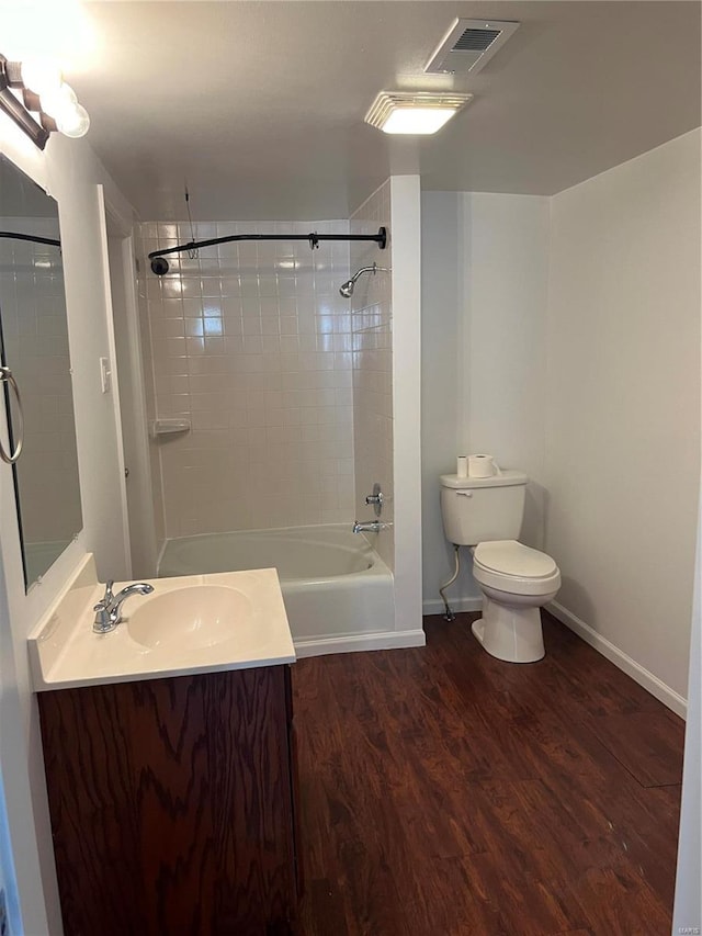 full bathroom with hardwood / wood-style floors, tiled shower / bath, toilet, and vanity