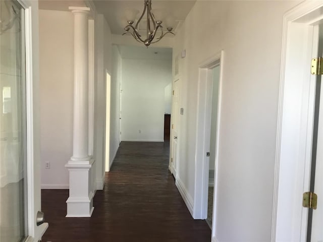 hallway featuring dark hardwood / wood-style flooring, a chandelier, and decorative columns