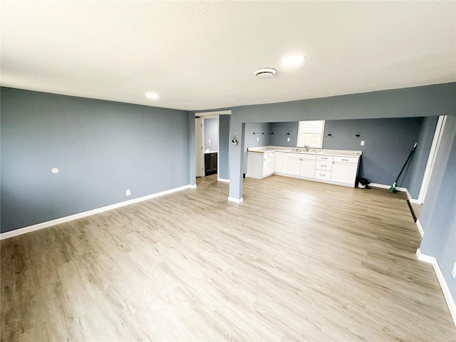 unfurnished living room featuring light hardwood / wood-style flooring and sink