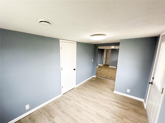 unfurnished room with a textured ceiling and light wood-type flooring