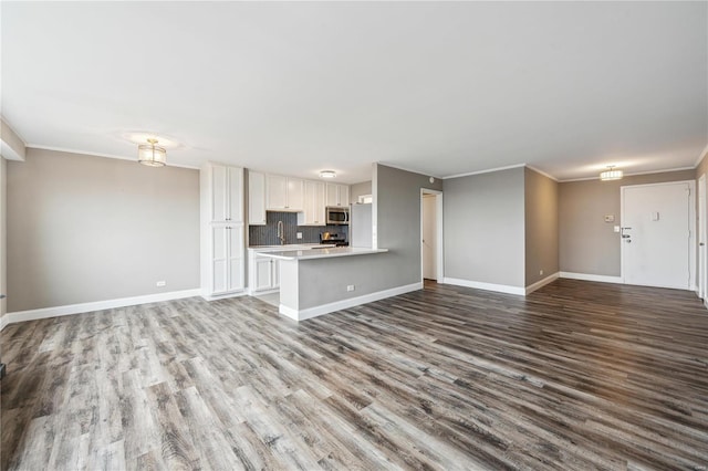 unfurnished living room featuring hardwood / wood-style floors, sink, and crown molding