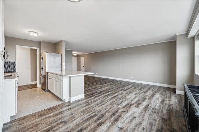 kitchen with decorative backsplash, appliances with stainless steel finishes, crown molding, light hardwood / wood-style flooring, and white cabinetry