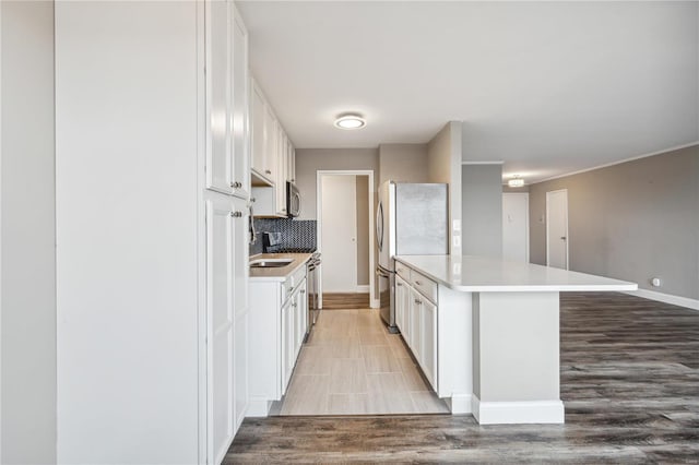 kitchen featuring a breakfast bar, white cabinets, light wood-type flooring, tasteful backsplash, and stainless steel appliances