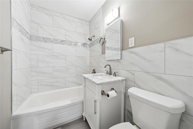 full bathroom with vanity, toilet, tile walls, and tiled shower / bath