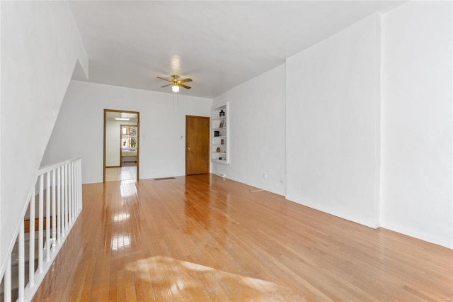 empty room with ceiling fan, light hardwood / wood-style flooring, and built in features