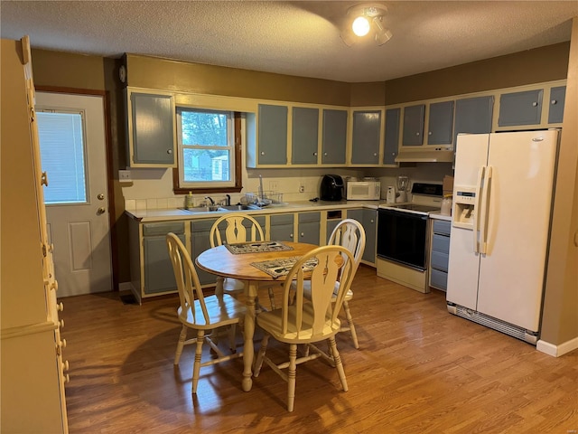 kitchen with white appliances, a textured ceiling, sink, and light hardwood / wood-style flooring