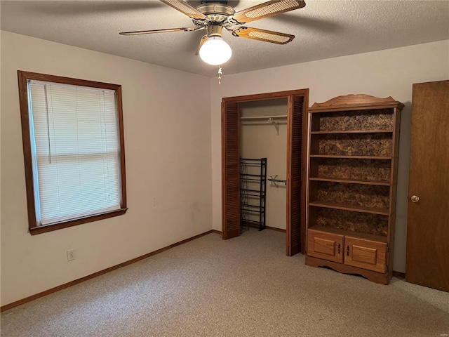 unfurnished bedroom featuring a textured ceiling, light colored carpet, ceiling fan, and a closet