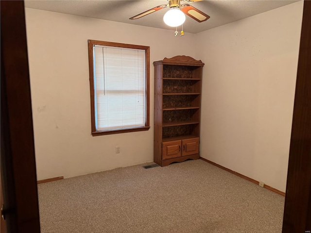 spare room with ceiling fan and light carpet