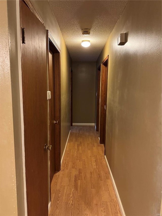 hallway featuring light hardwood / wood-style floors and a textured ceiling