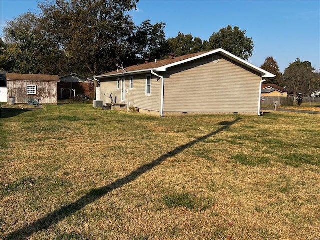 view of property exterior featuring central AC unit, a yard, and a storage unit