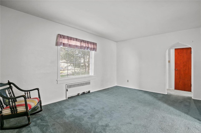 unfurnished room with dark colored carpet and radiator