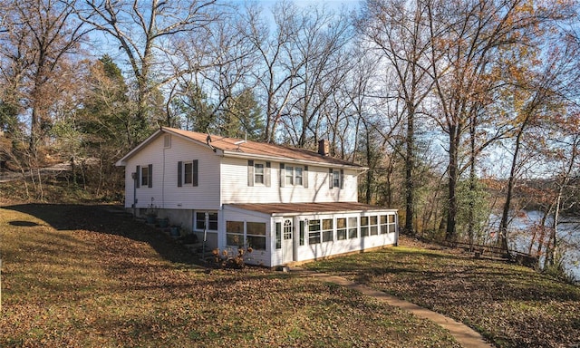 back of house featuring a sunroom and a lawn