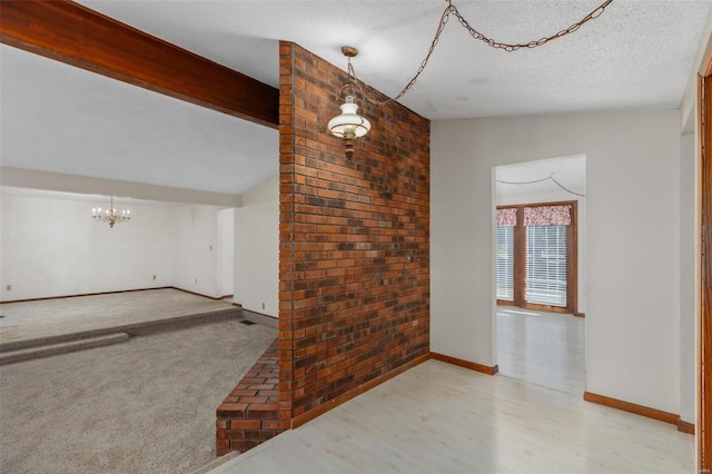 unfurnished living room featuring lofted ceiling, a textured ceiling, light carpet, and brick wall