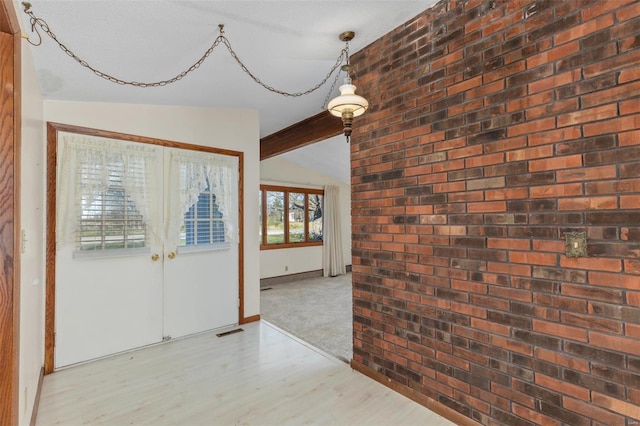 foyer featuring french doors, a textured ceiling, light hardwood / wood-style flooring, and lofted ceiling