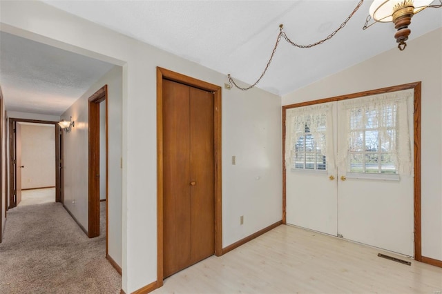 foyer entrance featuring light hardwood / wood-style floors, french doors, a textured ceiling, and lofted ceiling