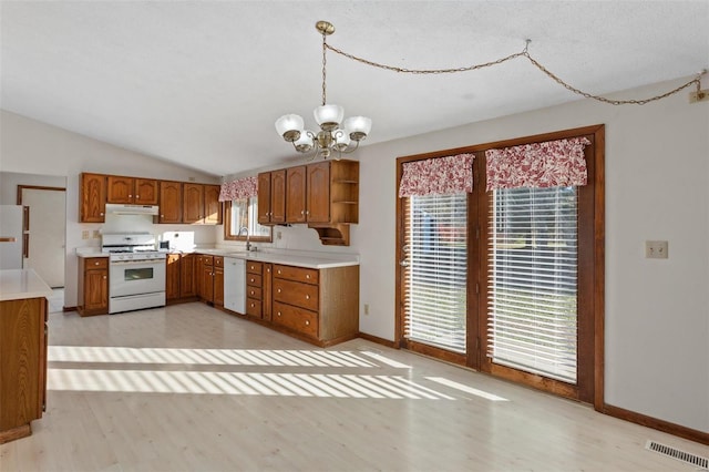 kitchen featuring pendant lighting, an inviting chandelier, white appliances, light wood-type flooring, and vaulted ceiling