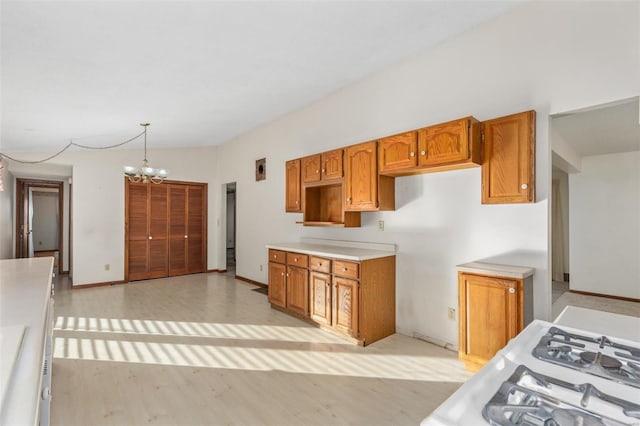 kitchen with hanging light fixtures, white gas range, a chandelier, and light wood-type flooring