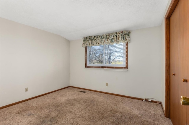 unfurnished bedroom featuring a closet, vaulted ceiling, carpet flooring, and a textured ceiling