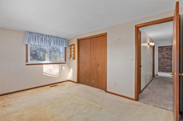 unfurnished bedroom with a textured ceiling, light carpet, and a closet