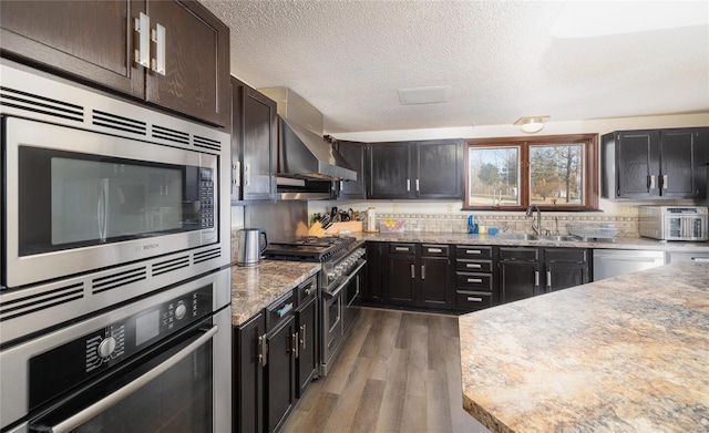 kitchen featuring hardwood / wood-style floors, sink, stainless steel appliances, dark brown cabinets, and a textured ceiling