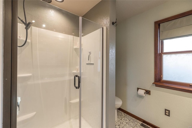 bathroom featuring a shower with door and toilet