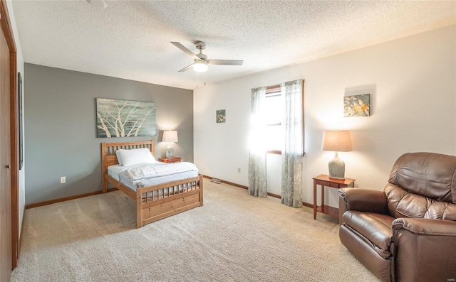 bedroom featuring ceiling fan, light colored carpet, and a textured ceiling