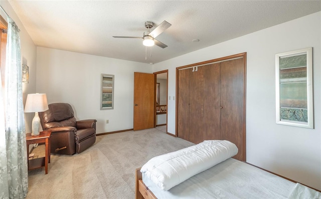 bedroom featuring light carpet, ceiling fan, a closet, and a textured ceiling