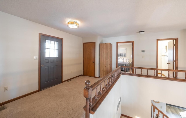 carpeted foyer with a textured ceiling