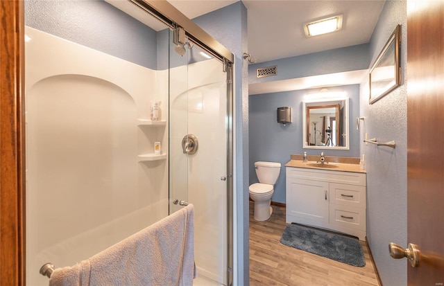 bathroom with an enclosed shower, vanity, wood-type flooring, and toilet