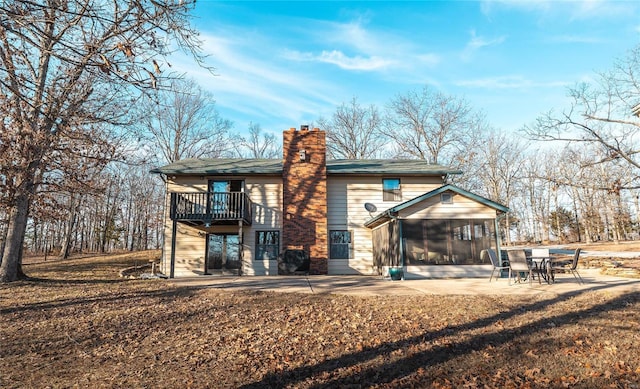 rear view of property featuring a patio, a sunroom, and a lawn