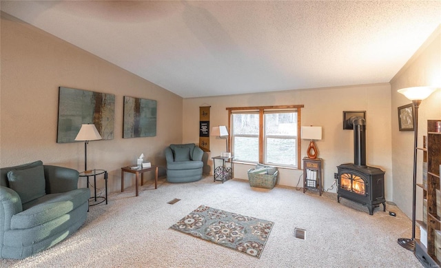 carpeted living room with vaulted ceiling, a textured ceiling, and a wood stove