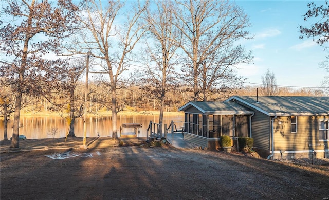 view of yard featuring a water view, a dock, and a sunroom