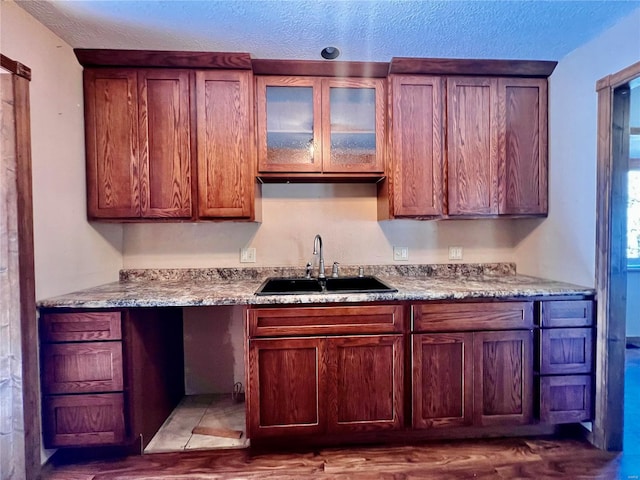 kitchen featuring sink, light stone counters, and a textured ceiling