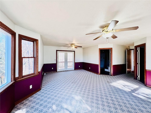 empty room featuring french doors, a textured ceiling, carpet flooring, lofted ceiling, and ceiling fan