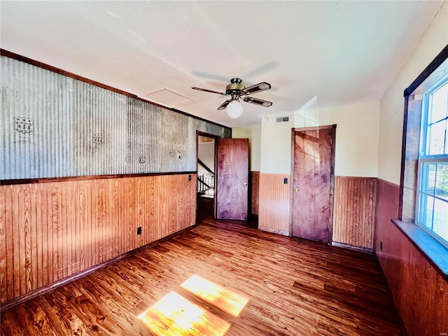 empty room featuring wood-type flooring, wooden walls, and a textured ceiling