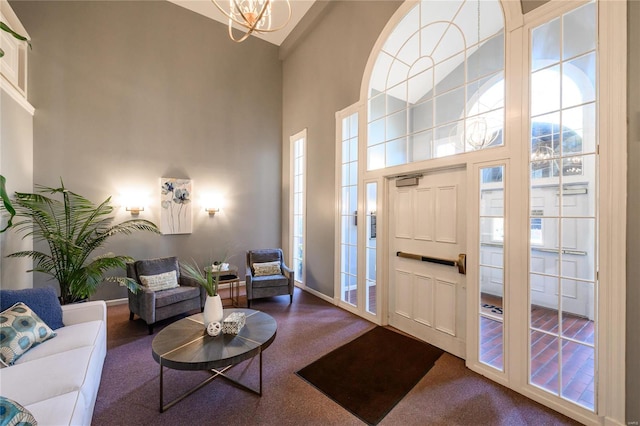 foyer featuring carpet flooring, a notable chandelier, and a towering ceiling