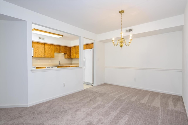 kitchen featuring pendant lighting, white refrigerator, sink, light colored carpet, and kitchen peninsula