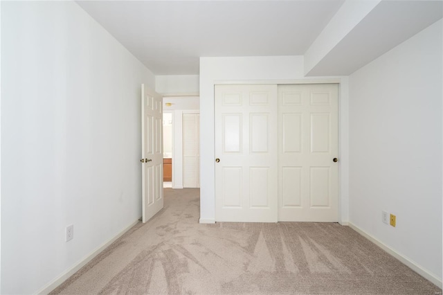 unfurnished bedroom featuring light carpet and a closet