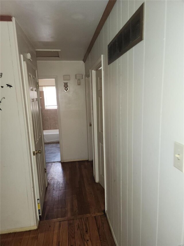 corridor featuring ornamental molding and dark wood-type flooring