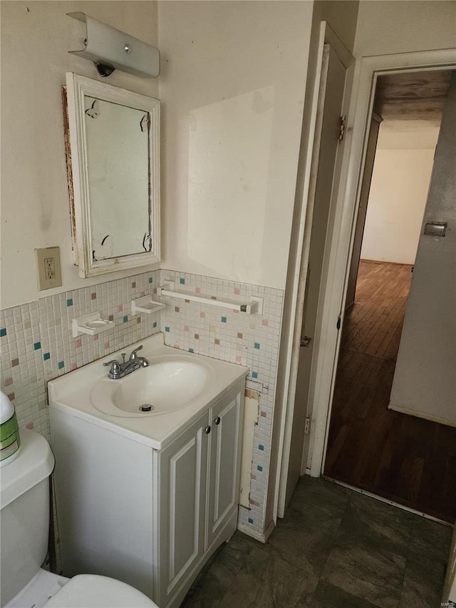 bathroom with hardwood / wood-style floors, vanity, toilet, and tile walls