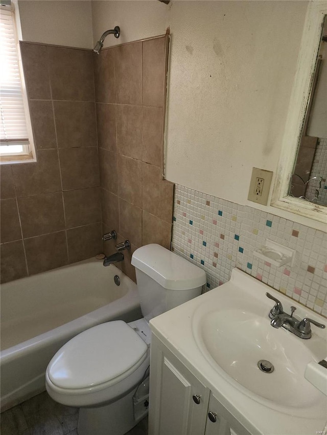 full bathroom with decorative backsplash, vanity, tiled shower / bath combo, tile walls, and toilet