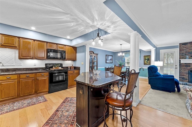 kitchen featuring sink, pendant lighting, black appliances, and light hardwood / wood-style floors