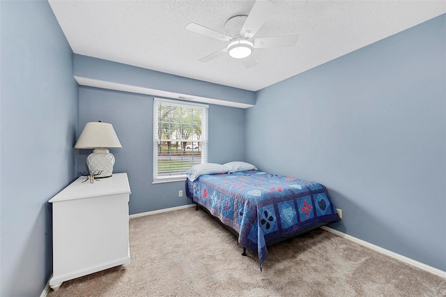 bedroom featuring ceiling fan, light colored carpet, and a textured ceiling