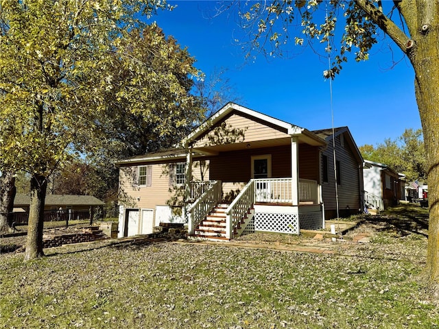 view of front of home with a front lawn, covered porch, and a garage