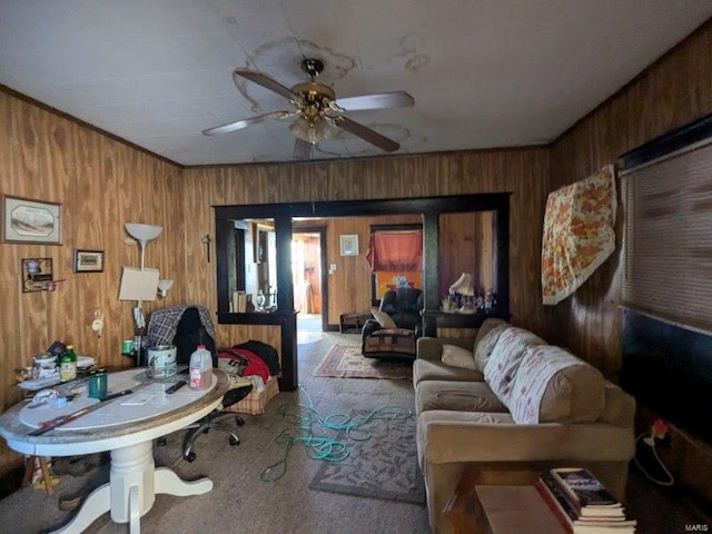 carpeted living room featuring wooden walls and ceiling fan