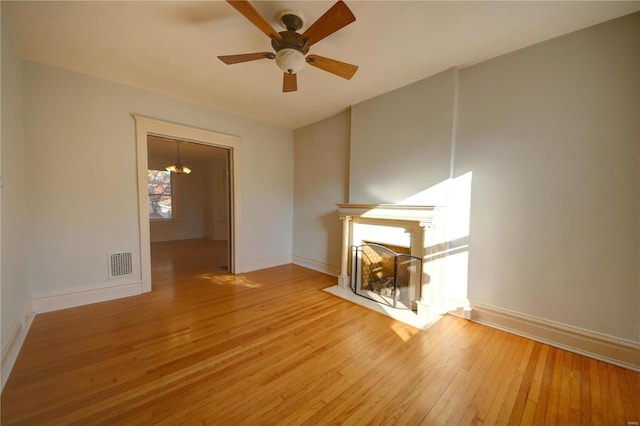 unfurnished living room featuring ceiling fan with notable chandelier and light wood-type flooring