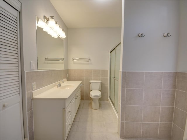 bathroom featuring vanity, tile patterned floors, toilet, tile walls, and a shower with shower door