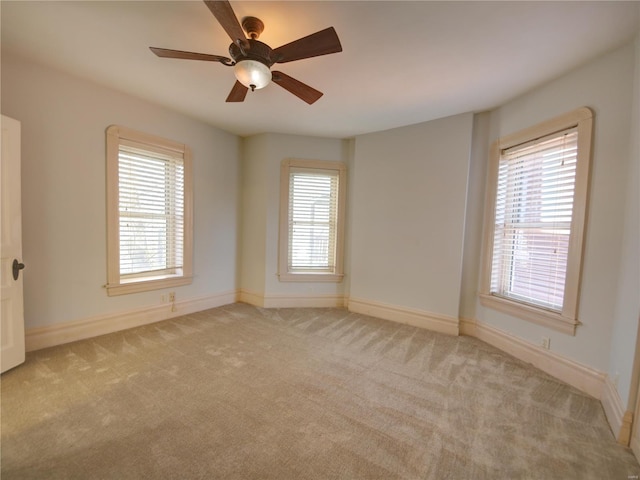 unfurnished room with a wealth of natural light, ceiling fan, and light carpet